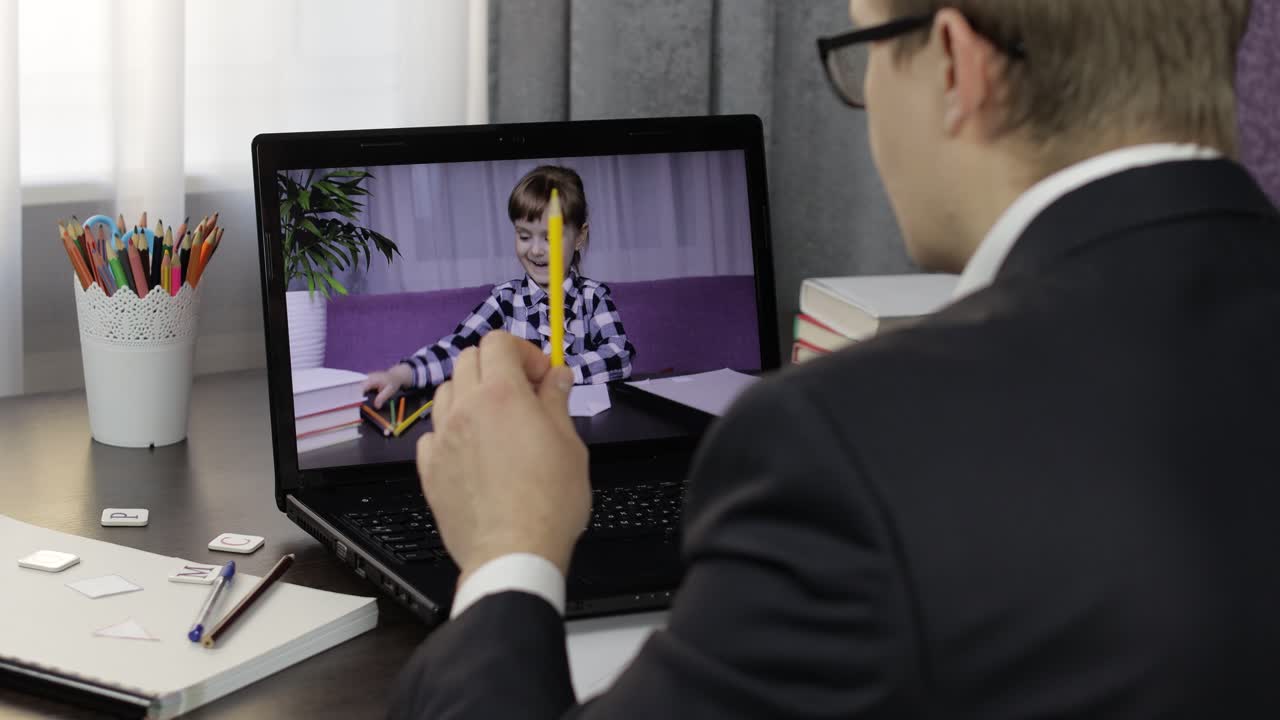 Man teacher making video call on laptop with little pupil. Distance education