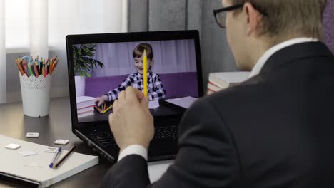 Profesor-Hombre-Haciendo-Videollamada-En-Una-Computadora-Portátil-Con-Un-Pequeño-Alumno.-Educación-A-Distancia