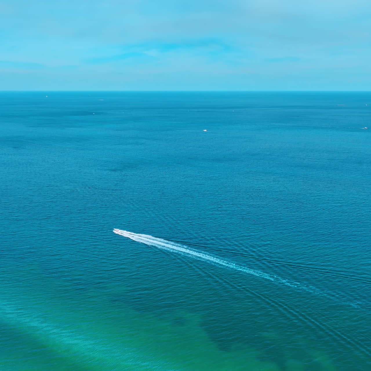 Motor boat moving quickly by the surface of immense azure waterscape. Top view on the Atlantic Ocean on sunny day.