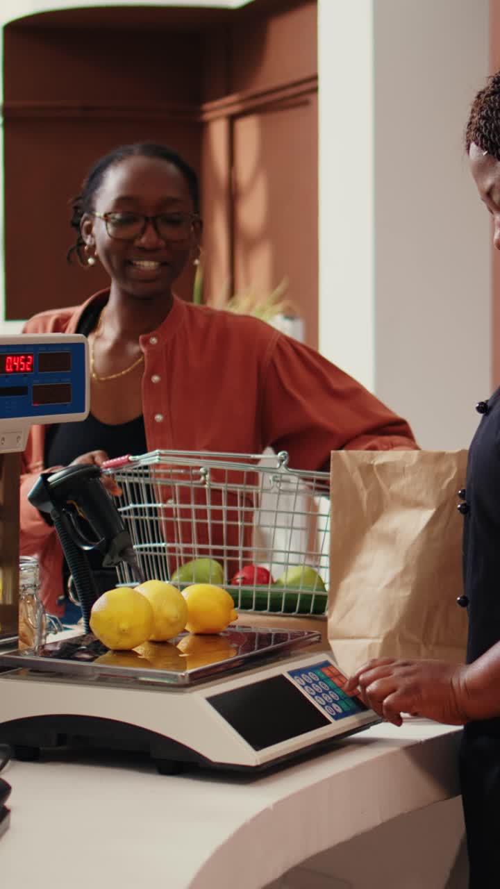 Vertical Video Retailer placing goods on electronic scale at cash register