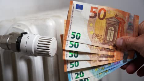 europe, italy , increase in the cost of bill for  gas and electricity causes increased price for the procurement of raw materials, money euro banknote and domestic heating radiator