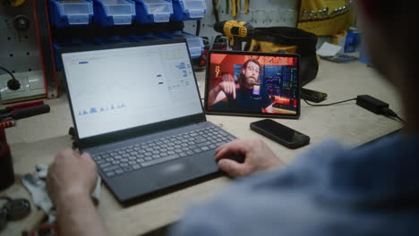 man checking real-time stocks and exchange market charts using laptop, watching online trading lesson on digital tablet. employee remote learning trading during working hours in workshop. close up.