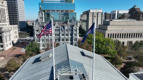 Banderas-De-Estados-Unidos-Y-Virginia-Ondeando-En-Lo-Alto-Del-Edificio-Del-Capitolio-En-El-Centro-De-Richmond,-Virginia