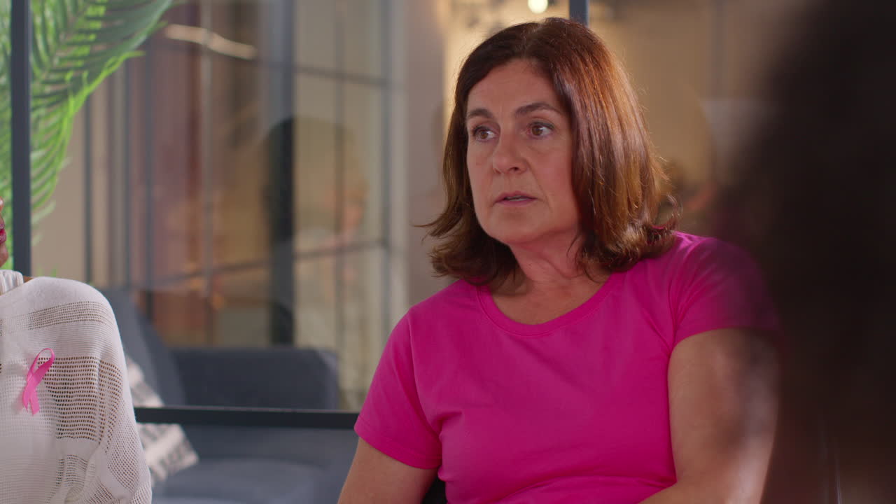 Mature Woman Talking At Meeting Of Therapy Support Group For Breast Cancer Treatment Patients Sitting At Table