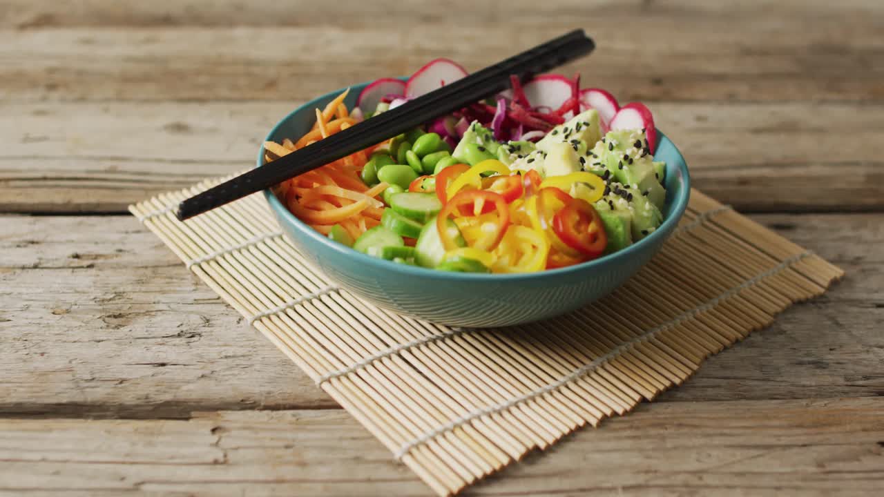 Composition of bowl of rice and vegetables with chopsticks on wooden background