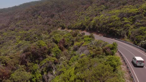 antena de drones que sigue a una furgoneta conduciendo por una pintoresca carretera costera