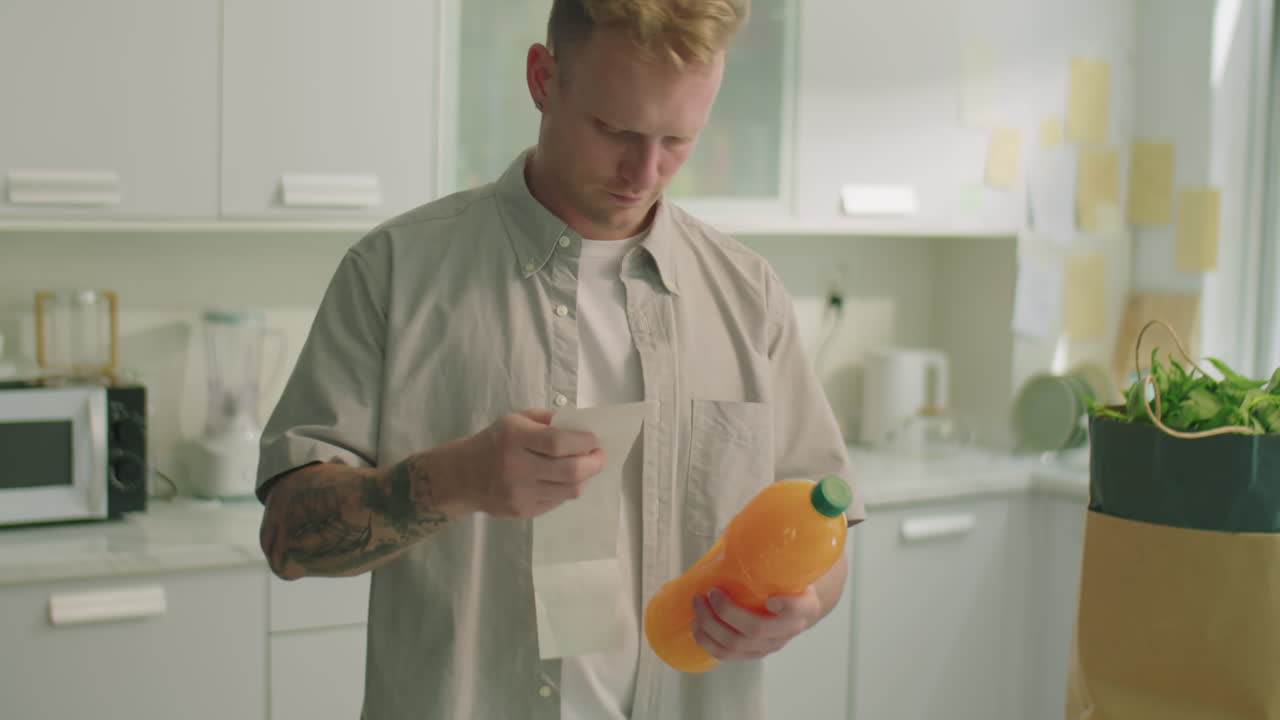 Man Reading Receipt from Supermarket in Kitchen