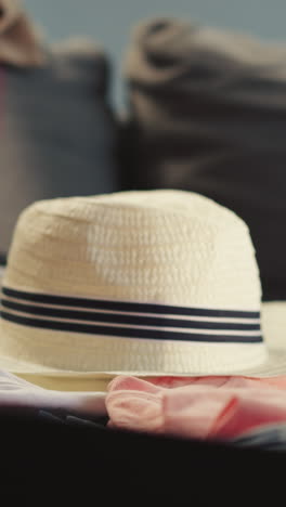 little girl puts straw hat into suitcase and mother gathers and checks up luggage on sofa closeup. family with child prepares for long journey