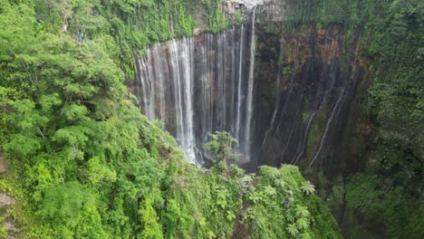 aerial descent into lush jungle canyon at tumpak sewu waterfall, java