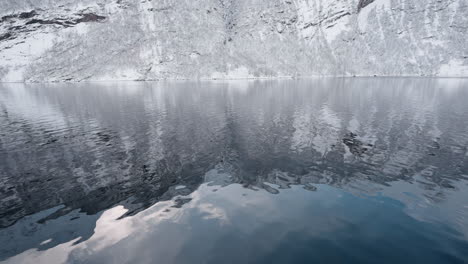 Slow-motion-POV-of-a-winter-ferry-boat-ride-in-Geirangerfjord-to-Geiranger,-Norway,-with-snowy-mountains-and-captivating-fjord-views