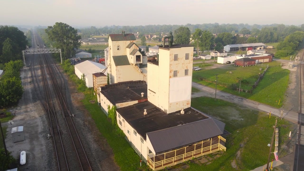 Vista aerea ravvicinata di silos per il grano vicino ai binari della ferrovia in una piccola città, Carleton, Michigan, USA.