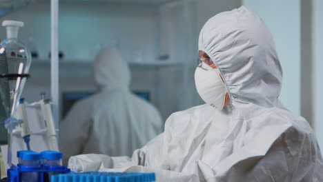 close up of scientist in protection suit typing on pc