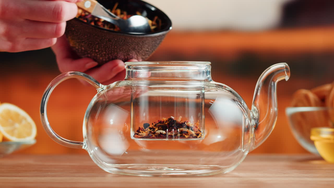 Pouring loose leaf tea into a glass teapot