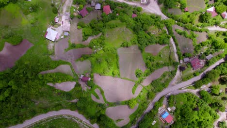 Top-down-view-of-a-remote-Georgian-mountain-village-with-houses,-trees,-and-farms