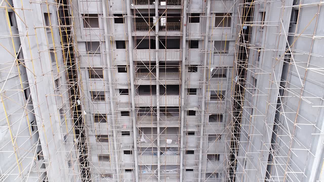 Aerial rising shot of building under construction with unrecognizable workers