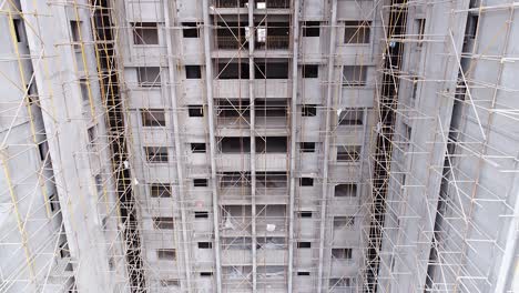 aerial rising shot of building under construction with unrecognizable workers