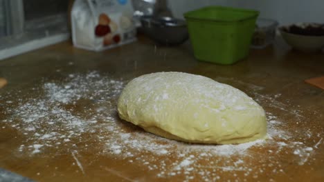 dry white flours sprinkled by hand over freshly risen dough ball on kitchen table top, filmed as close up shot in slow motion