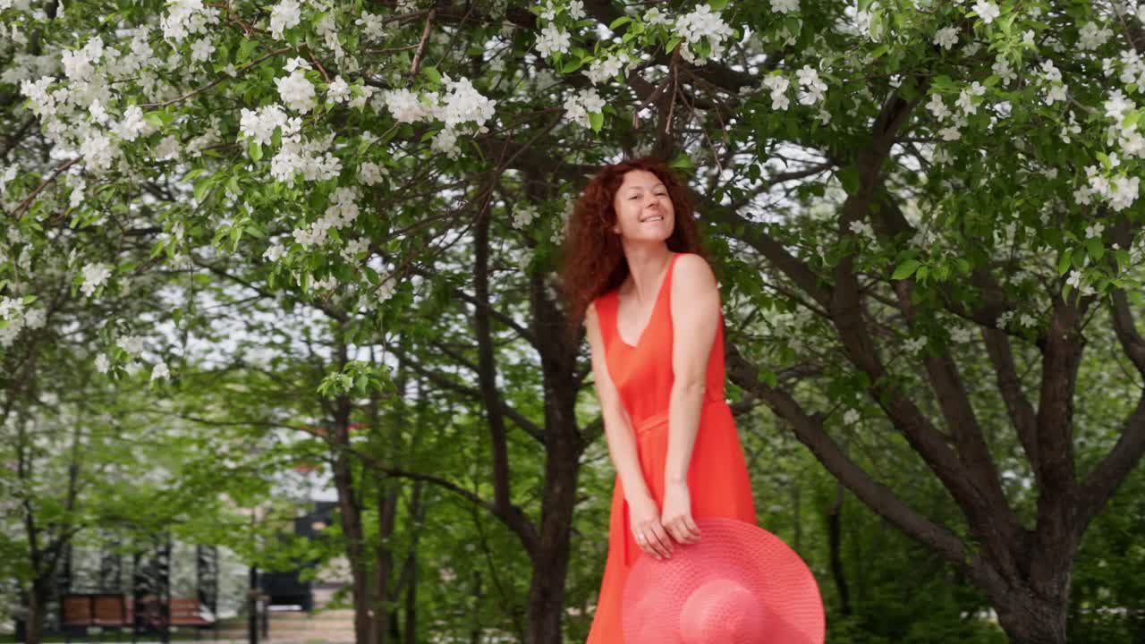 Woman in a red dress walking in a blooming park