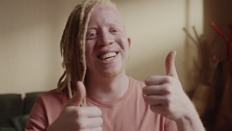 a man with dreadlocks smiling and giving two thumbs up