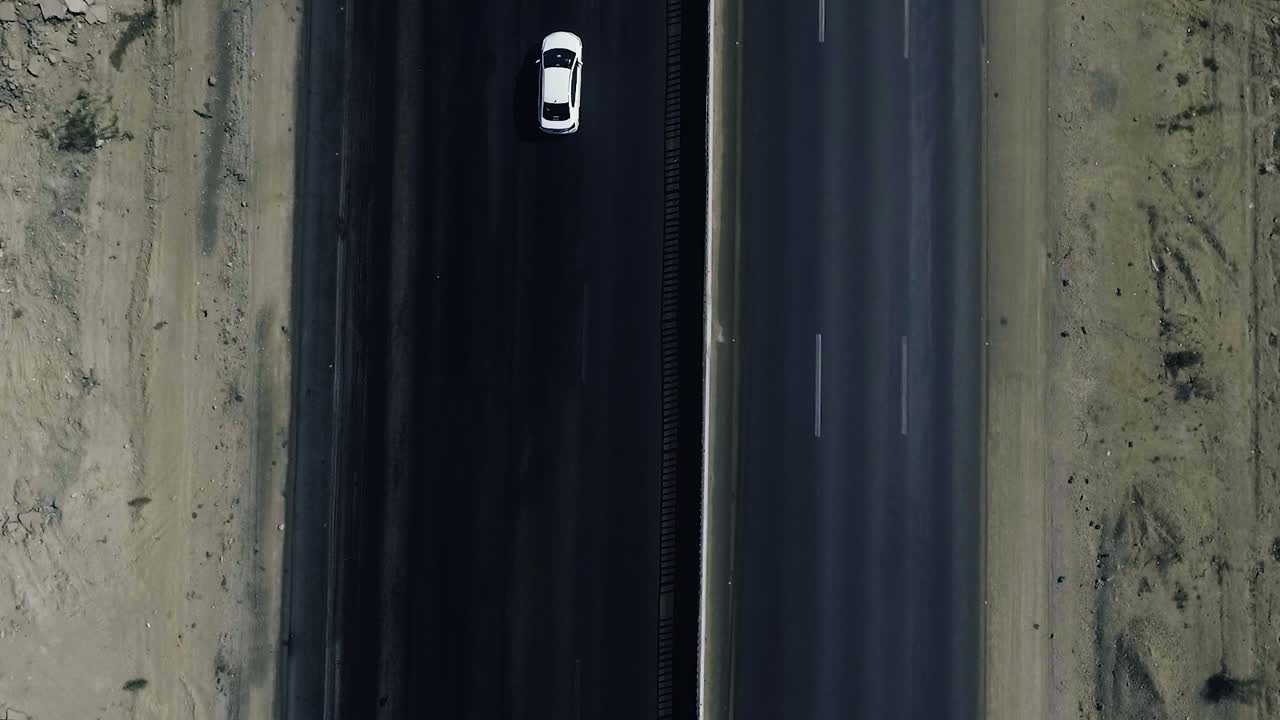 una vista superior aérea en cámara lenta de un arrastrero pesado y dos autos blancos que se mueven en una carretera en las áreas del norte