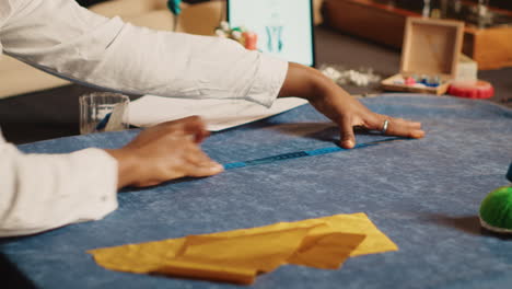 Young-tailor-using-meter-on-fabric