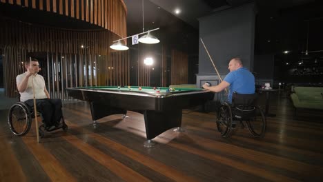 hombres adultos con discapacidad en silla de ruedas juegan al billar en el club