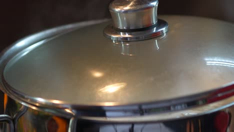 boiling water in a silver pot with a lid with rising steam