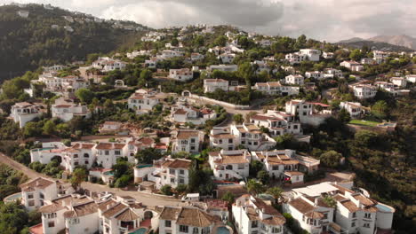 orbit aerial 4k shot of small town mountains white houses green trees day cloudy suburban in pego, alicante, spain