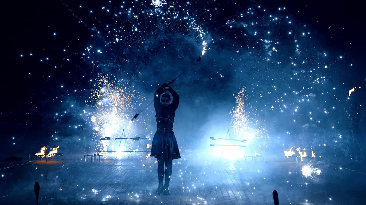 Fantastic fire show performed by the female artist. Woman moves the stage props that produce sparks of firework.