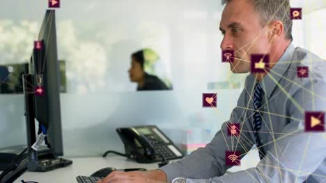 animación de globos de iconos digitales girando contra el hombre de negocios caucásico usando la computadora en la oficina