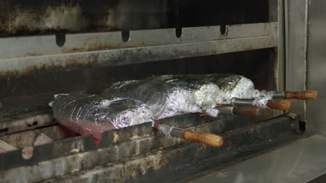 movimiento lento del cocinero poniendo carne envuelta en papel de aluminio en la parrilla de carbón