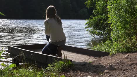 woman in solitude sits down on pier by lake