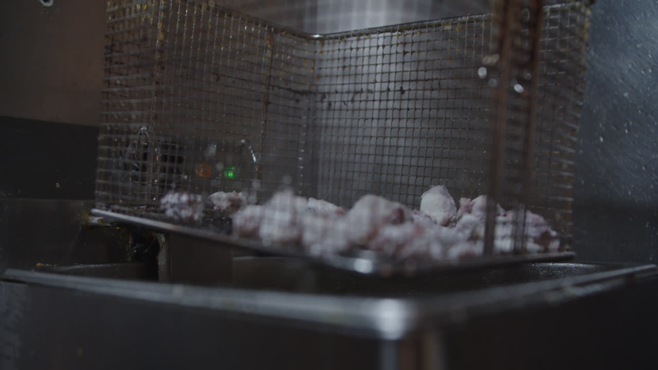 Food Being Lowered into a Deep Fryer in a Commercial Kitchen