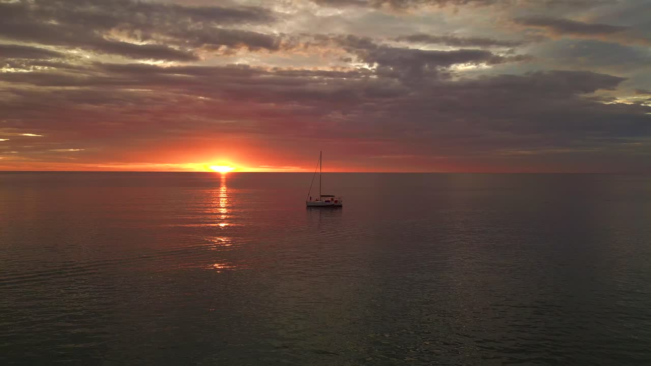 silueta velero naranja rayos de sol en el mar