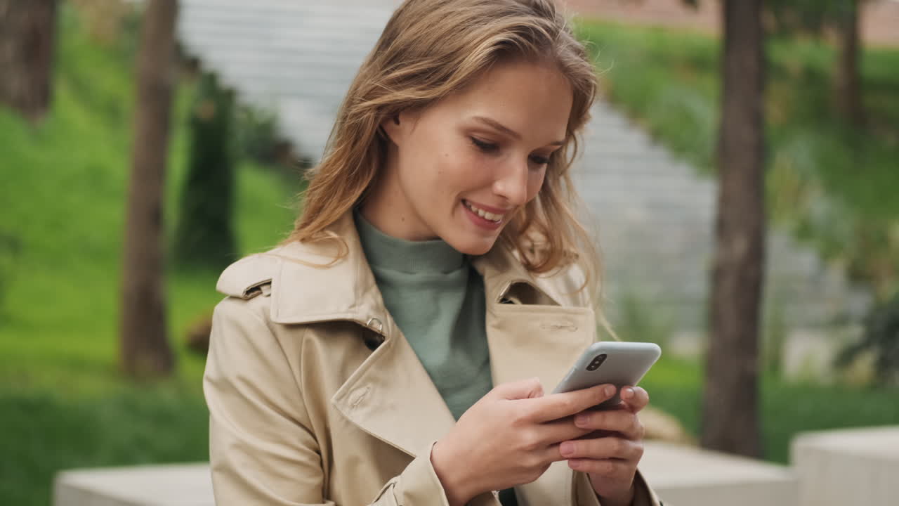 Caucasian female student using smartphone and looking at the camera.
