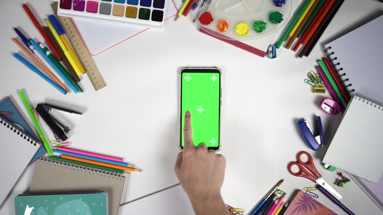 conjunto de 26 gestos en la pantalla verde del teléfono inteligente sobre una mesa blanca entre los accesorios escolares