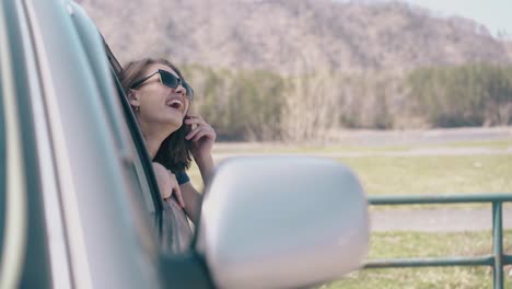 mujer riendo con el cabello corto se ve fuera de auto en tierras de cultivo