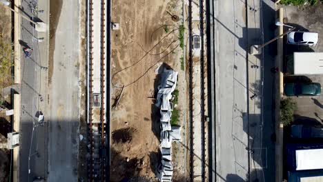 aerial slow forward drone shot of an empty light rail on construction in jaffa, israel, surrounded by dirt and concrete