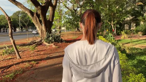 young brunette woman back view walking in city on cracked unsafe sidewalk