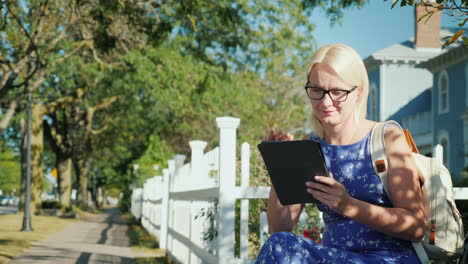 Frau-Benutzt-Tablette-Durch-Weißen-Lattenzaun