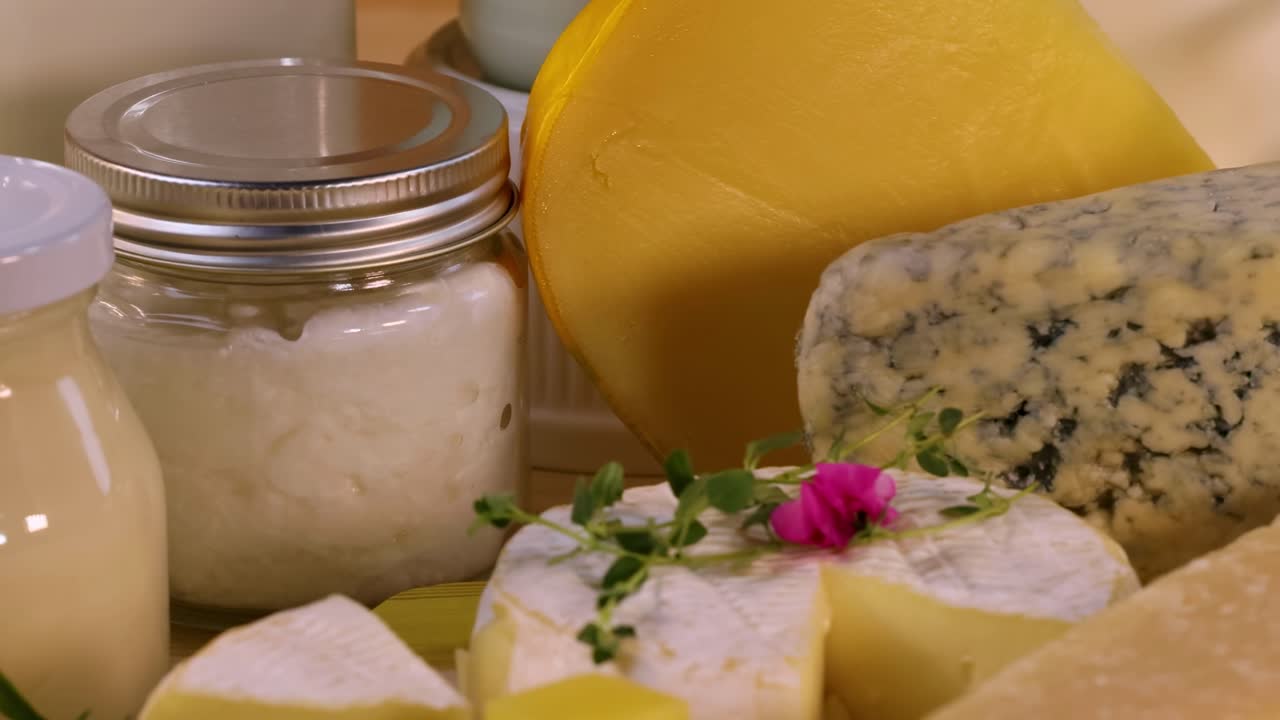 A selection of cheeses and cream jars arranged with decorative flowers and herbs.