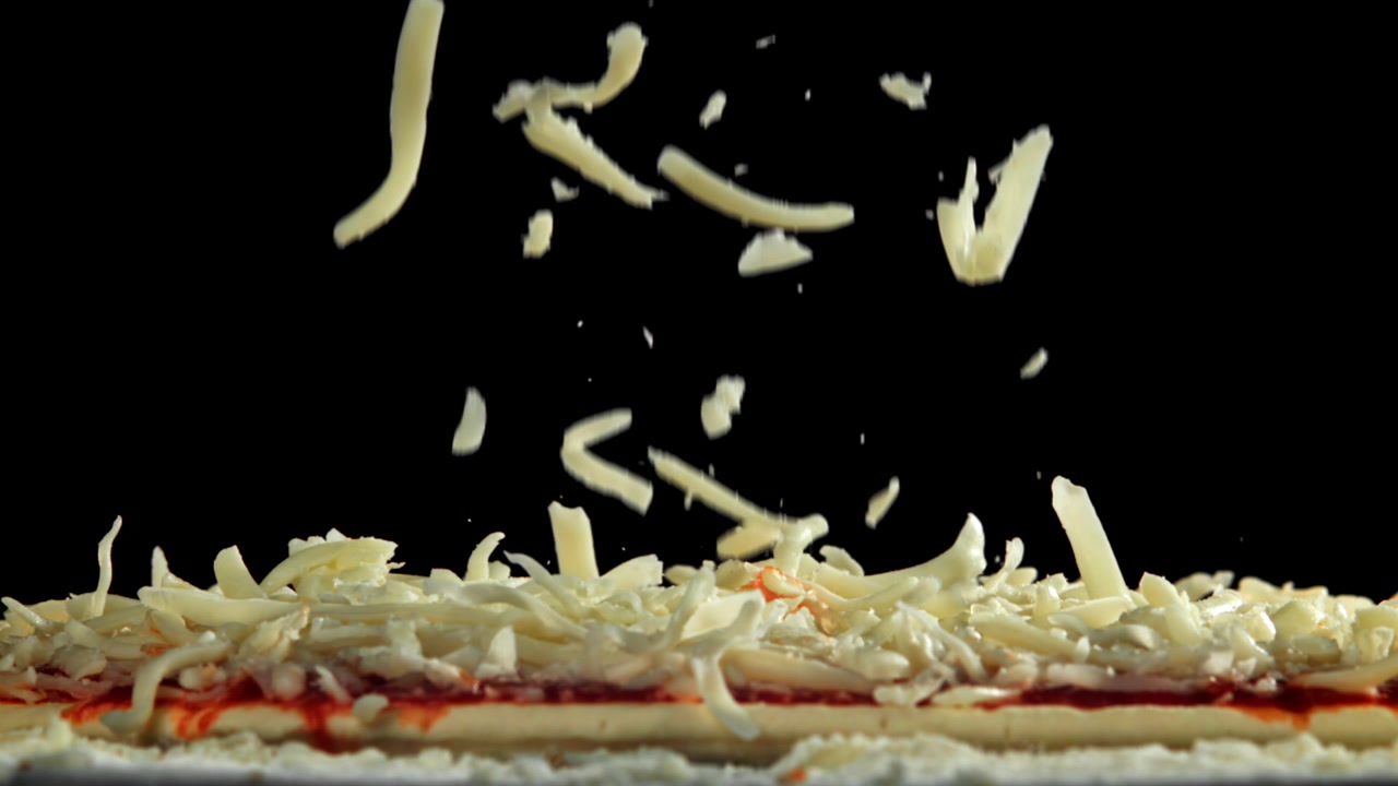 Shredded Mozzarella Cheese Falling onto Pizza Dough