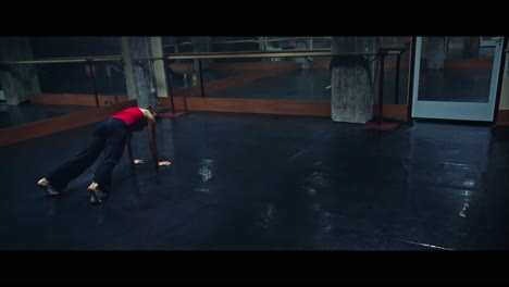 a young woman practices modern dancing and ballet in a moody room full of mirrors