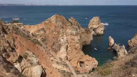 Menschen-Steigen-Treppen-Hinunter,-Während-Boote-In-Der-Nähe-Von-Lagos,-Portugal,-In-Tip-Of-Piety-Einfahren