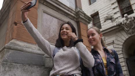 Low-Angle-Ansicht-Eines-Kaukasischen-Und-Gemischtrassigen-Mädchens,-Das-Draußen-Ein-Selfie-Macht