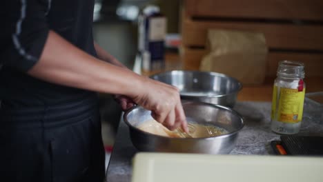 Milk-and-egg-mixture-being-whisked-and-aerated-in-metal-bowl,-filmed-medium-closeup-slow-motion-shot