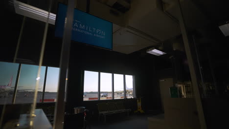 the sun peeks through the window at hamilton's john c monroe airport prior to boarding early in the morning.