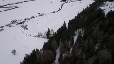 Revelación-Aérea-De-Una-Pista-De-Carreras-Nevada-En-Un-Lugar-Remoto-Del-Valle-Cerca-Del-Bosque-Oscuro