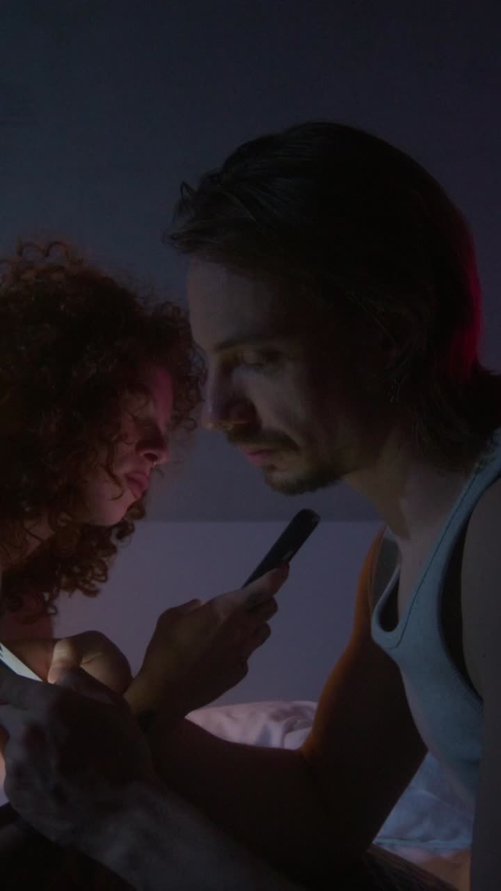 밤에 침대에서 드폰을 사용하는 부부