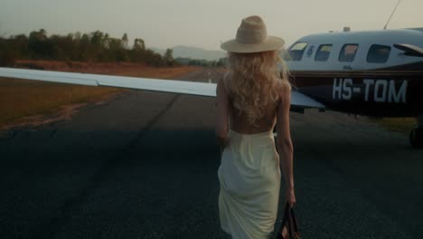 woman in a cream dress walking at the airport with an expensive bag